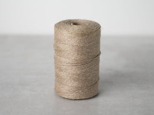 A picture of a spool of beige natural linen warp string.